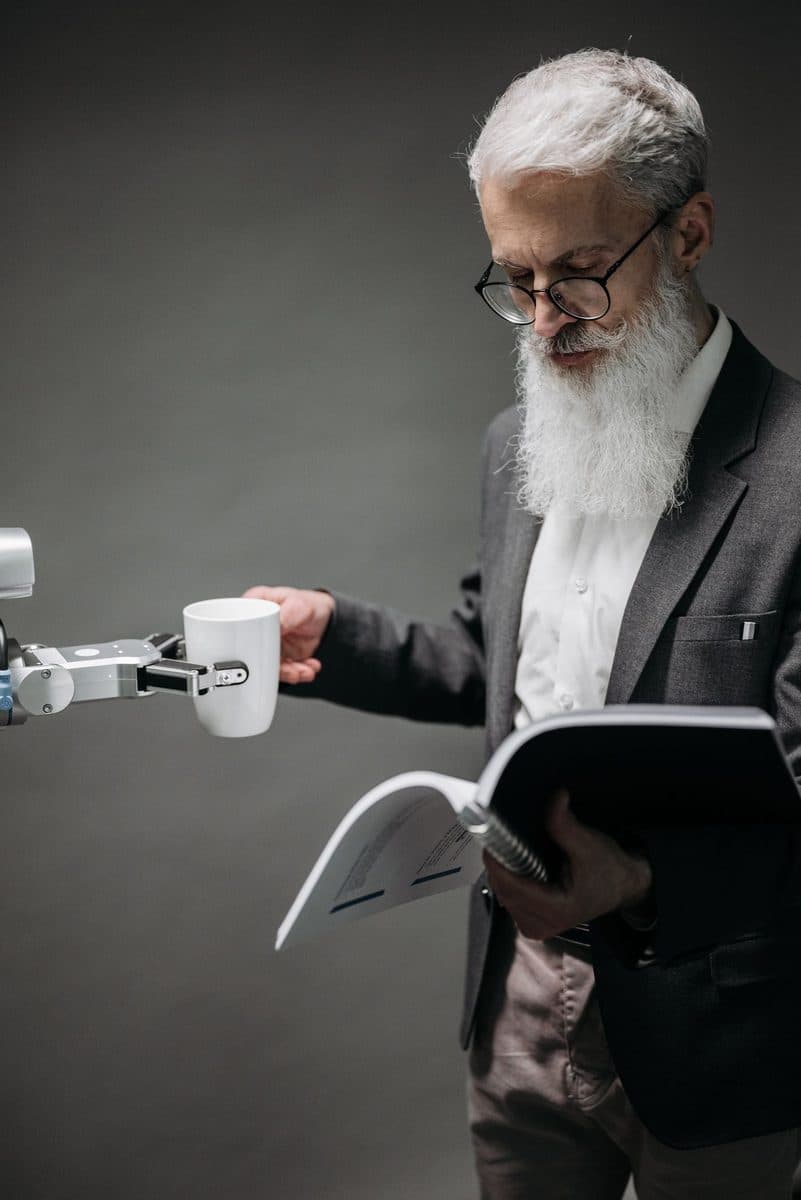 A robotic arm handing a cup to a person reading a document