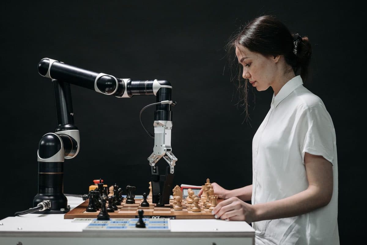 A person playing chess against a robotic arm on a dark stage