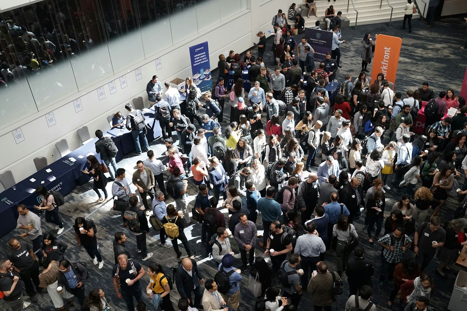 A busy conference floor seen from above, full of people networking
