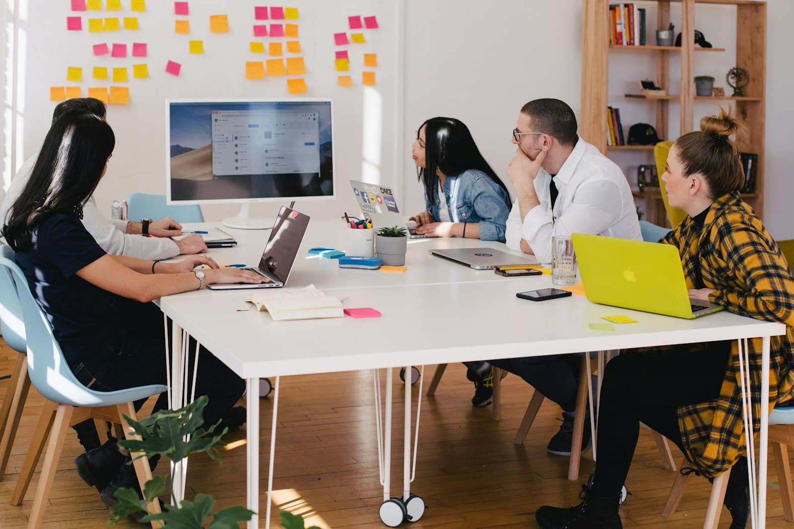 A project team working around a table beside a wall of colourful sticky notes