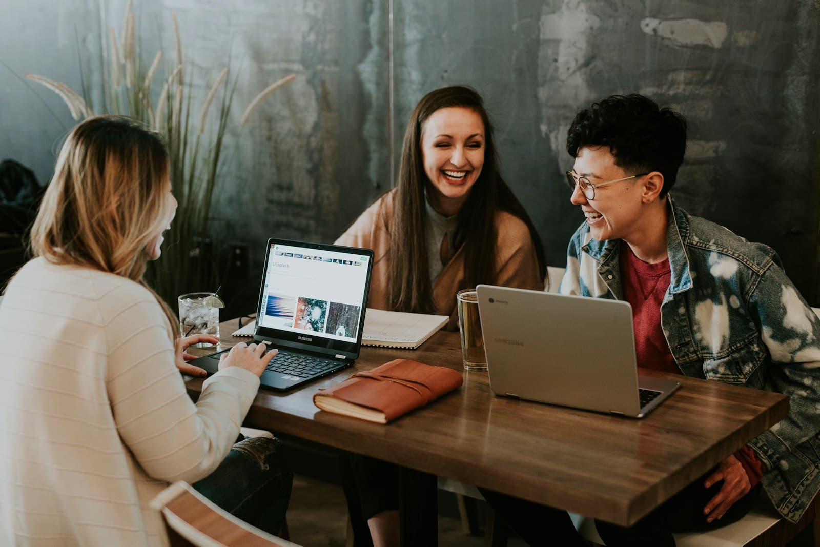 Three colleagues smiling at a laptop during a hands-on working session